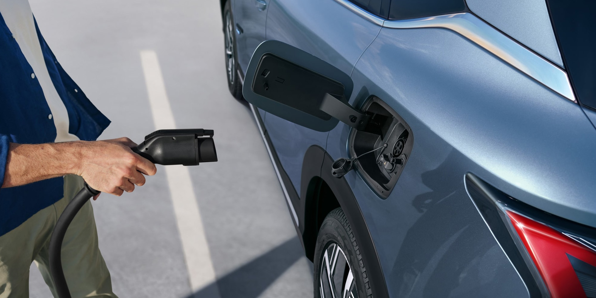 Persona conectando cargador en vehículo Chevrolet eléctrico.